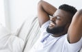 Pleased black man relaxing at home on couch Royalty Free Stock Photo