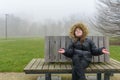 Enjoying a winter walk in the park. Teenage girl on a bench in cold weather in a warm jacket Royalty Free Stock Photo