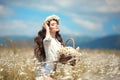 Enjoyment. Beautiful young girl with basket of flowers over chamomile field. Carefree happy brunette woman with healthy wavy hair Royalty Free Stock Photo