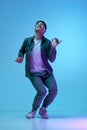 Full-length of young asian guy in casual clothes posing with positive mood, dancing against blue background in neon Royalty Free Stock Photo