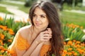 Enjoyment. Happy smiling brunette woman with arms near face embracing the golden marigold flowers