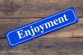 Enjoyment street sign on wooden background