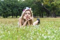 Enjoyment young woman with flower on her hair blowing on dandelion flowers while lying on green grass in the park. Lovely girl Royalty Free Stock Photo