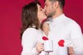 An enlarged photo of kissing lovers on a red background in white sweaters and white cups of tea for your advertisement Royalty Free Stock Photo