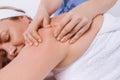 Enlarged photo where the hands of the masseur massage the back of a woman with an inverted white towel.