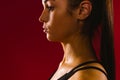 An enlarged profile photo of a caucasian girl sweating after physical exertion against a red background. Dark photo of Royalty Free Stock Photo