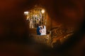 Enloved groom kissing his charming bride on old wooden stairs with the background of luxury interior. Peephole-stylized