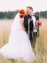 Enloved wedding couple enjoy a moment of happiness and lovingly look at each other on wheat field Royalty Free Stock Photo