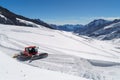 An enormous red snow plow moves along the glacial surface at Jungfraujoch