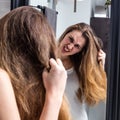 Enraged young woman pulling out her dry tousled long hair