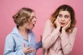 The enraged young woman screams at her friend in rage. The victim of aggression and psychological violence in fear closes her ears