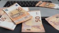 Enriching through the internet and technology cost concept: several 50 euro banknotes fall on the keyboard of an open laptop