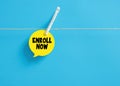 Enroll now message on a speech bubble hanging on clothesline with a clothespin Royalty Free Stock Photo