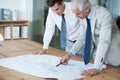 Ensuring the blueprints are perfect. Two corporate architects going over the plans of a building together.