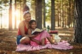 Ensuring her little one stays a keen reader. a mother and her little daughter reading a book together in the woods. Royalty Free Stock Photo