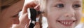 Ent doctor examining sore ear of small child using otoscope