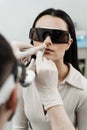 ENT doctor with laser treats girl patient in protective glasses. Laser treatment inflammation of the nasal lining, runny Royalty Free Stock Photo