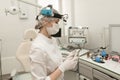 An ENT doctor in a modern ENT office of a hospital in a white coat and mask, holding an otoscope in his hands Royalty Free Stock Photo