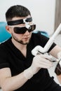 ENT doctor in protective glasses holding surgical laser and doing laser treatment inflammation of the nasal lining Royalty Free Stock Photo