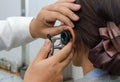 ENT physician checking patient's ear using otoscope with an inst