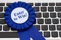 Enter to win message on a blue prize ribbon on keyboard