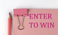 ENTER TO WIN word on pink paper with pink pencil