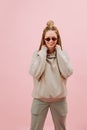 Entertained woman in sunglasses with stylish blond afro braids over pink