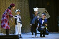 Entertainer holding the microphone to Crimean Tartar children in a native costumes helping them to sing the song on stage. Royalty Free Stock Photo