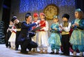 Entertainer holding the microphone to Crimean Tartar children in a native costumes helping them to sing the song on stage. Royalty Free Stock Photo