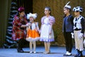 Entertainer holding the microphone to Crimean Tartar children in a native costumes helping them to sing the song on stage. Royalty Free Stock Photo