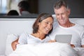 Entertainment in bed. a happy mature couple sitting in bed with a digital tablet. Royalty Free Stock Photo