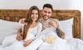 Entertainment in evening. Smiling man eating popcorn, woman presses button on remote control Royalty Free Stock Photo