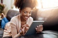 Entertainment for the homebody. Shot of a relaxed young woman using a digital tablet on the sofa at home.