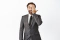 Enthusiastic businessman looking amazed with one eye, side of face, cover half with palm, standing in grey suit over