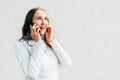 Enthusiastic Caucasian young woman in white jacket talks by mobile phone. Good news