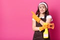 Enthusiastic cheerful woman standing isolated over pink background in studio, holding detergent and dirty washcloth in one hand,