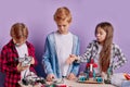 Enthusiastic concerned children assembling tech robots, future engineers