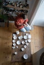 Concentrated creative ceramic woman sits at table and covers natural clay dishes with white lacquer