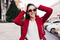 Enthusiastic dark-haired woman in sunglasses laughing in sunny day on the street. Outdoor portrait of magnificent