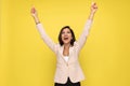 Enthusiastic girl in pink suit holding arms above head