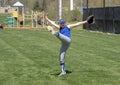 Enthusiastic girl softball player with arms outstretched and leg kicked high