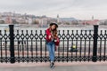 Enthusiastic girl wears blue jeans and hat posing with cup of coffee on city background. Outdoor full-length shot of Royalty Free Stock Photo