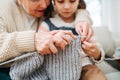 Enthusiastic granny tutoring her granddaughter, teaching her how to knit Royalty Free Stock Photo