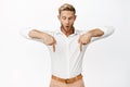 Enthusiastic handsome blond guy, pointing and looking down at something awesome, checking out interesting sale offer Royalty Free Stock Photo