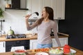 Enthusiastic housewife singing in ladle enjoying everyday cooking food process