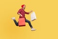 Enthusiastic joyful hipster trendy guy running in air with shopping bags in hands, hurrying to catch sale, flying