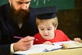 Enthusiastic kid studying with teacher. Father checking homework, helps to boy, son. Homeschooling concept. Teacher in Royalty Free Stock Photo