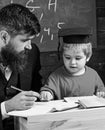 Enthusiastic kid studying with teacher. Father checking homework, helps to boy, son. Teacher in formal wear and pupil in Royalty Free Stock Photo