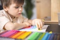 Enthusiastic male kid drawing multicolor rainbow paper sheet closeup early development art activity