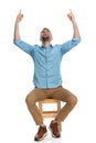 Enthusiastic man with chino pants looking up and pointing fingers in the air Royalty Free Stock Photo